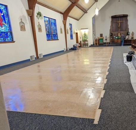 A man on his knees working on the church floor